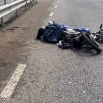 Повалений синій мотоцикл лежить на асфальті біля металевого відбійника