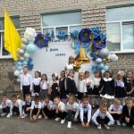 Першокласники та вчителька біля прикрашеного банера ліцею №3 на День знань