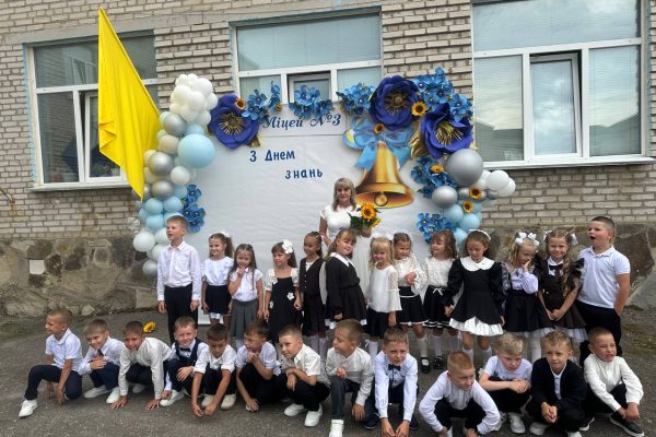 Першокласники та вчителька біля прикрашеного банера ліцею №3 на День знань