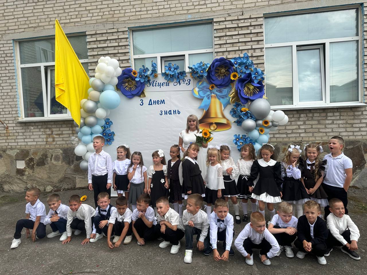 Першокласники та вчителька біля прикрашеного банера ліцею №3 на День знань